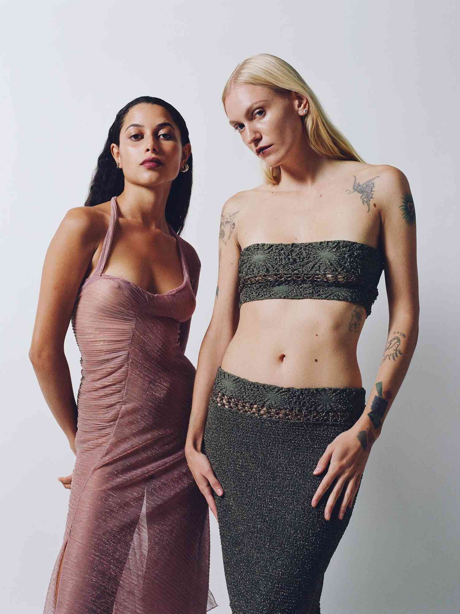 Two models, one wearing a sheer pink dress and the other wearing a crocheted bra top and skirt set