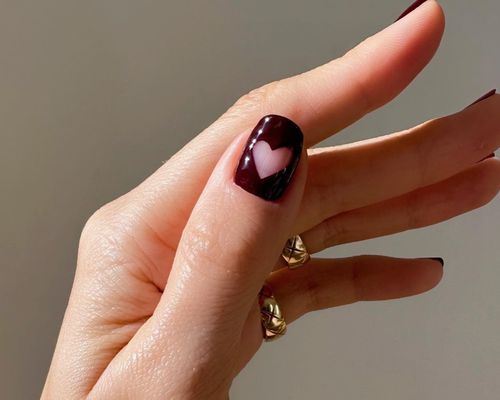 Close-up of dark burgundy manicure with negative space heart design