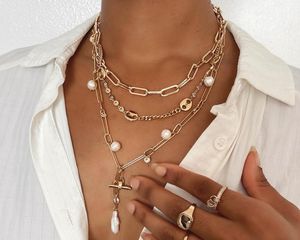 Close-up of woman wearing layered necklaces, rings, and white button-down shirt