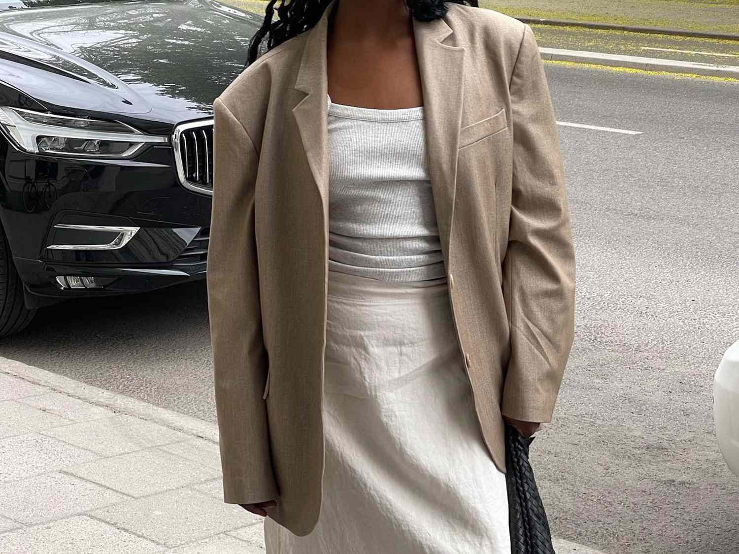 Close-up of woman wearing ribbed tank top, linen maxi skirt, and beige oversized blazer