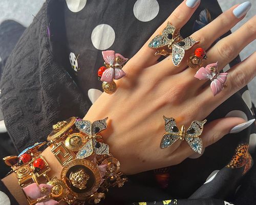 Hand with butterfly and ladybug Versace rings and bracelets