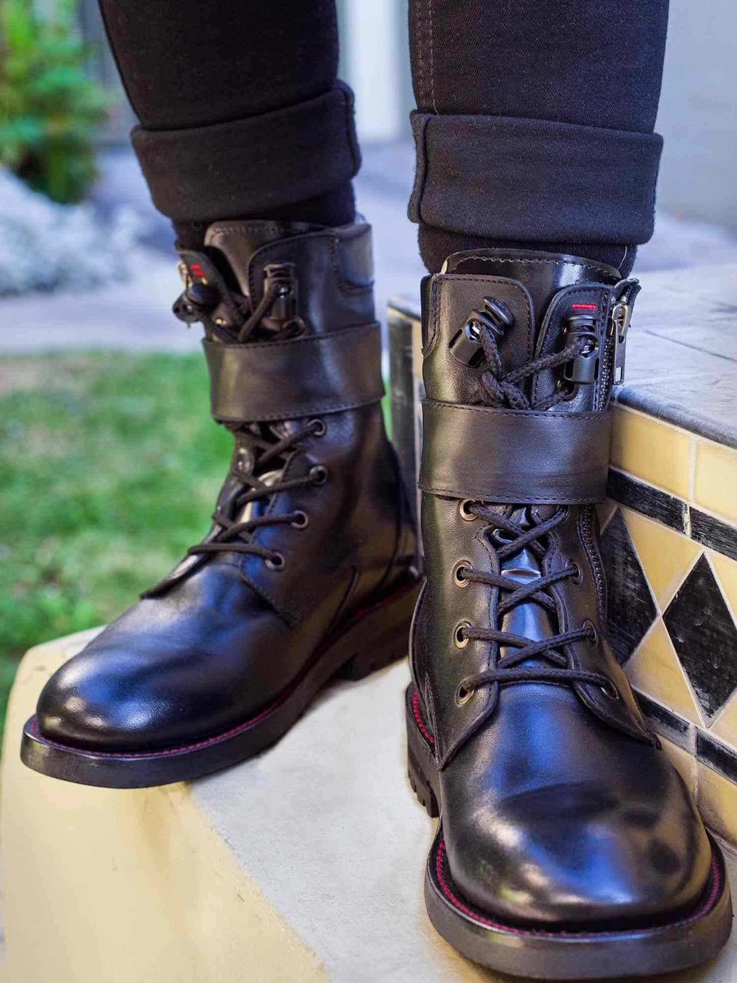 Close-up of person wearing black cuffed jeans and combat boots