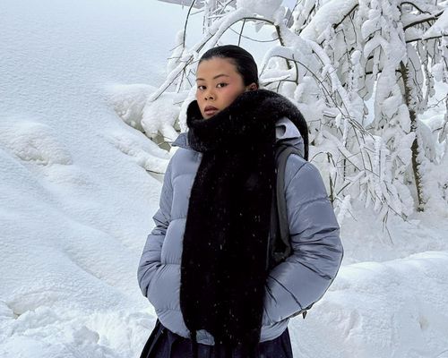 Woman wearing a cashmere scarf and puffer coat while standing in the snow