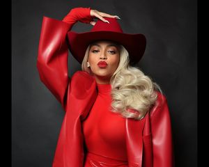 Beyonce wears a red turtleneck, leather trench coat, cowboy hat, and lipstick