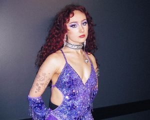 Chappell Roan wears a purple glitter fringe bodysuit and gloves with purple eyeshadow