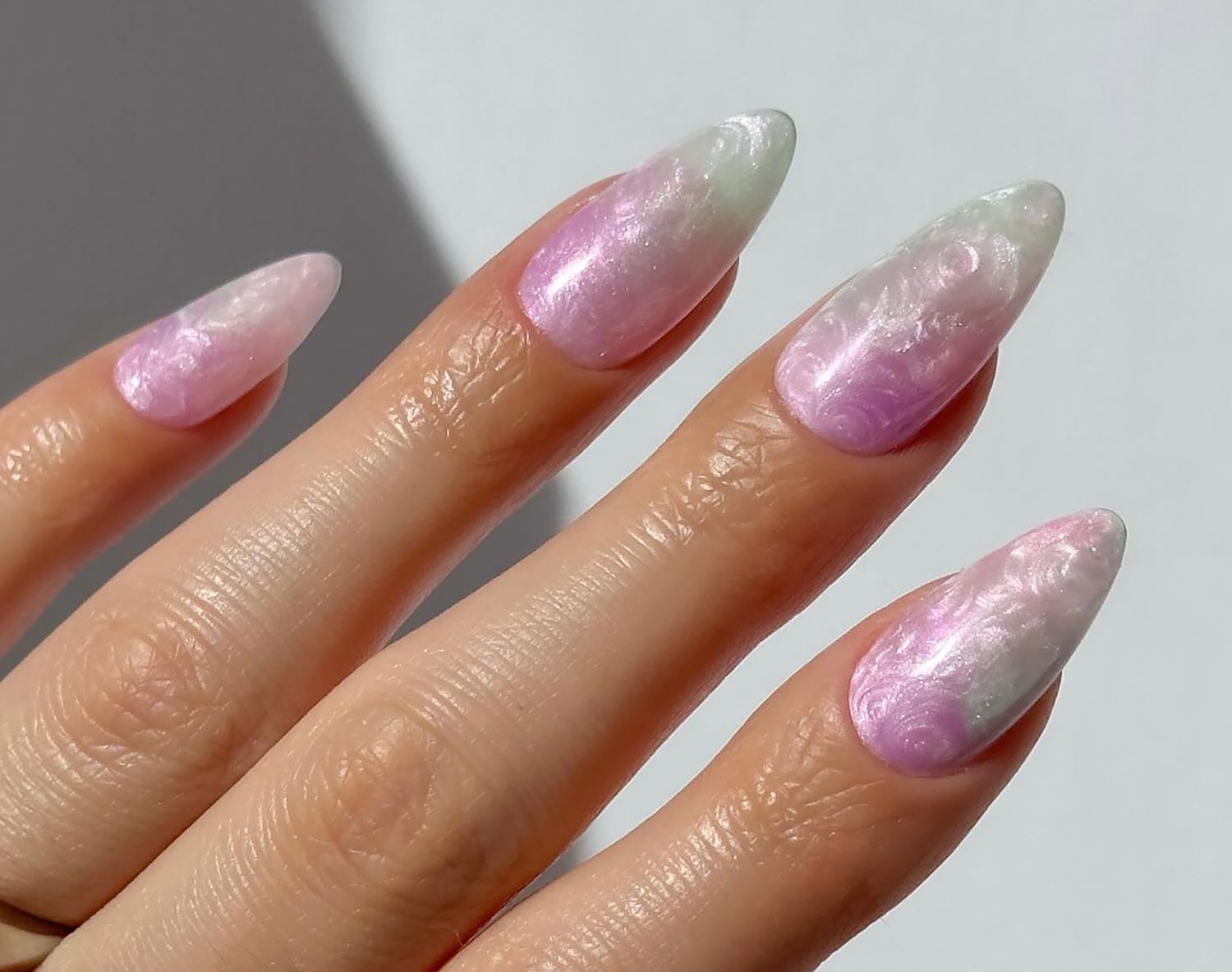 Close up of a swirly pearlescent manicure in light, dainty shades