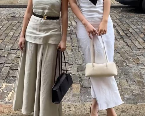 Close-up of two women wearing lightweight midi dresses and carrying Freja New York handbags