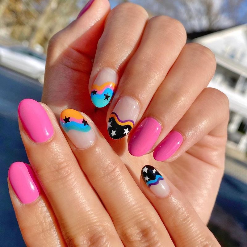 Mismatched manicure with neon pink nails and nude nails with stars and bright abstract designs