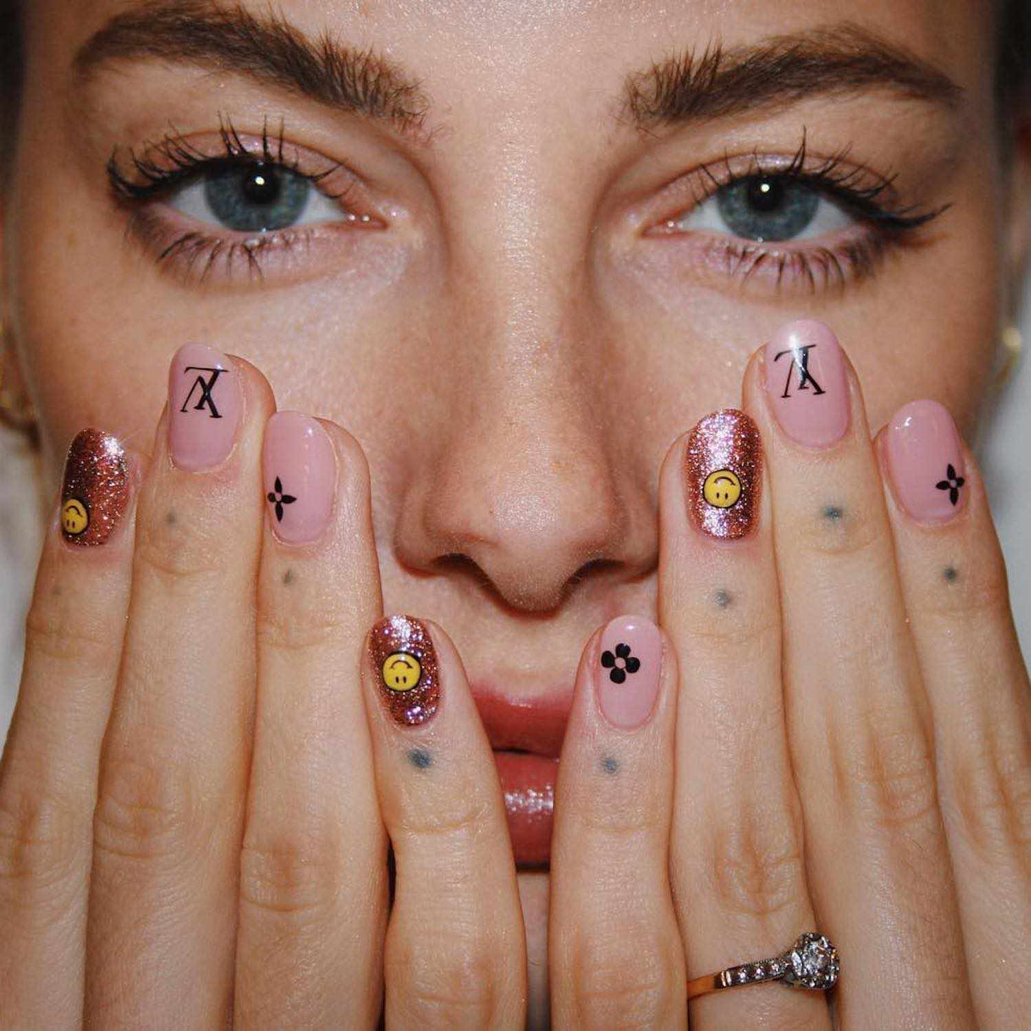 Louis Vuitton logo manicure with rose gold glitter smiley face accent nails