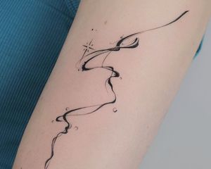 Close up of a forearm with an abstract, freehand tattoo of a flowing line