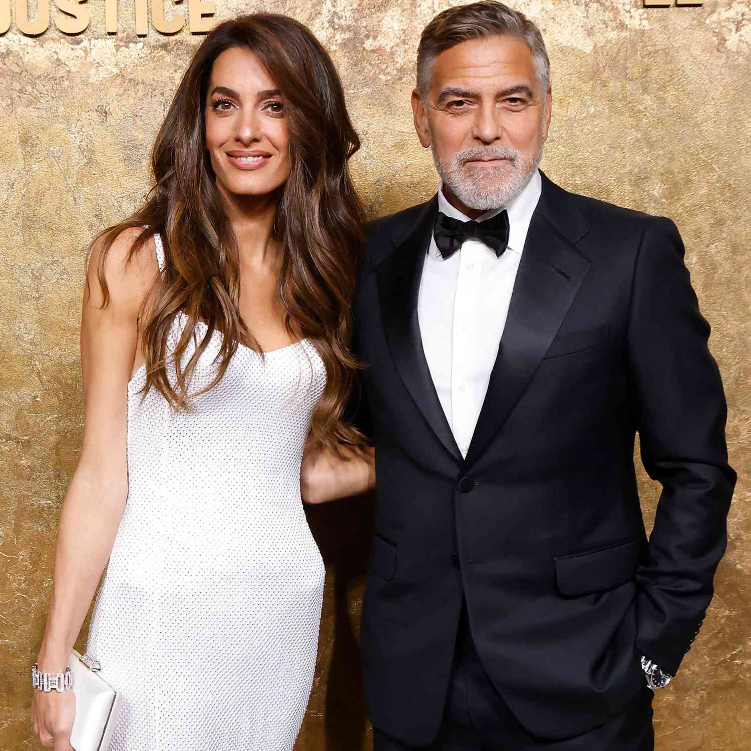 Amal Clooney at the Clooney Foundation for Justice Albie Awards in makeup by Charlotte Tilbury and a white gown with her husband George Clooney in a black tuxedo