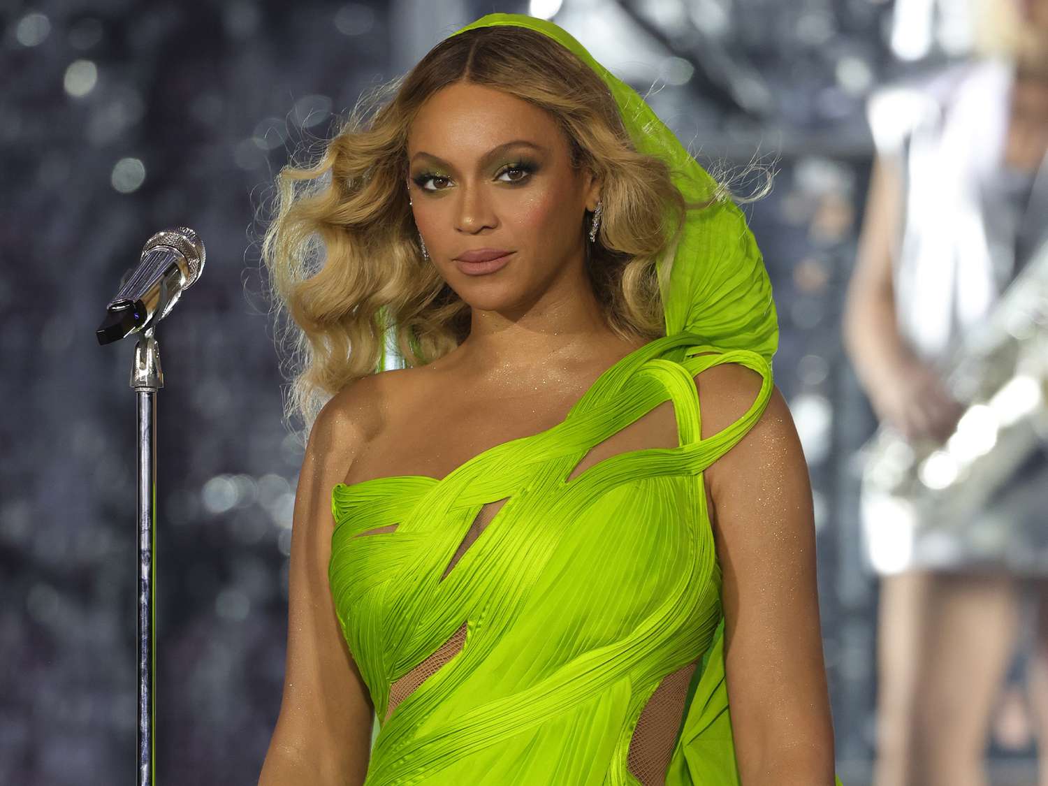 Beyonce at the renaissance tour in a lime green hooded dress and wavy blonde hair