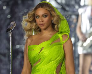 Beyonce at the renaissance tour in a lime green hooded dress and wavy blonde hair