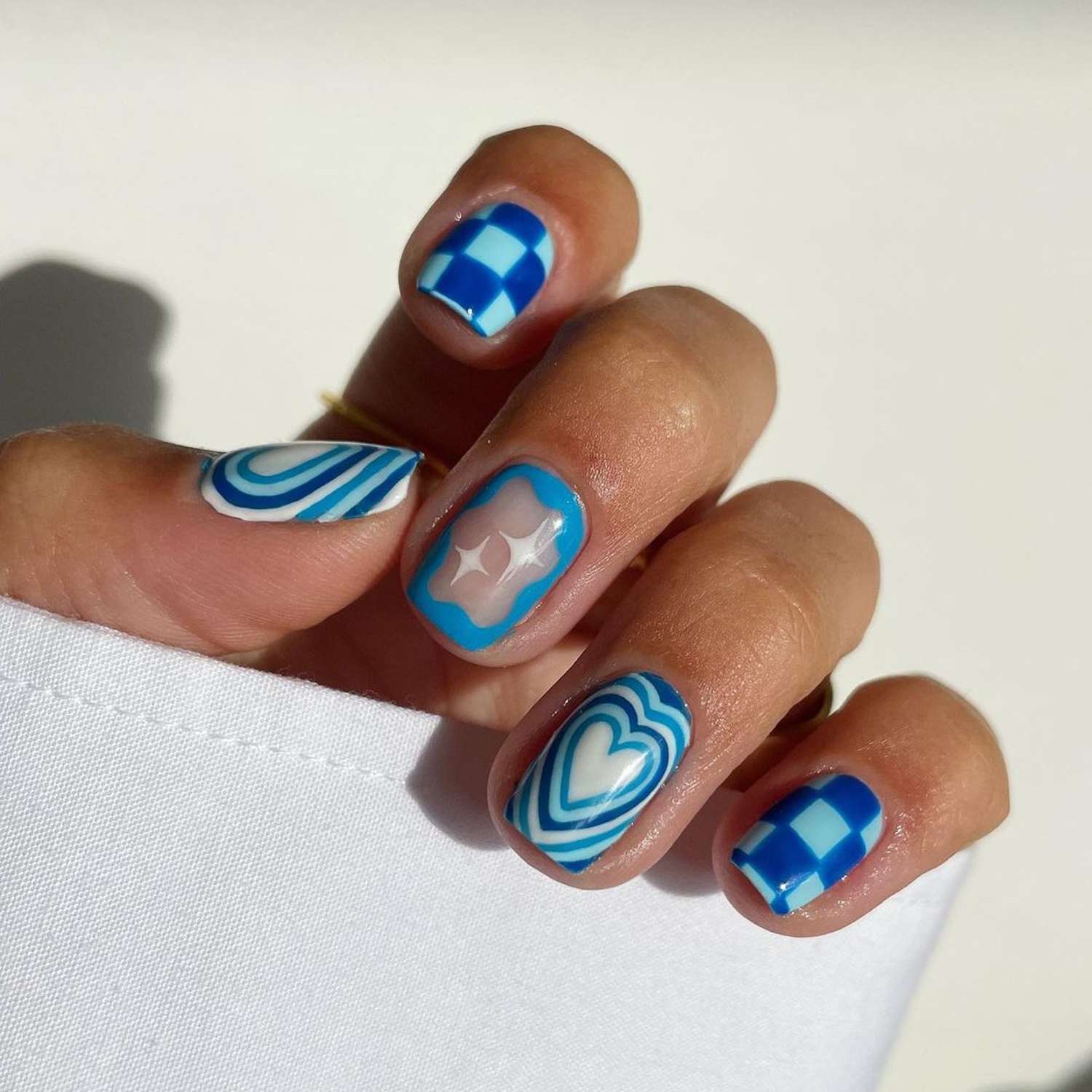 Blue and white mismatch nails with checker, sparkle, and heart accents