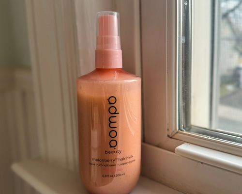 A bottle of Adwoa Beauty Hair Milk Leave-In Conditioner with Melonberry on a windowsill