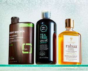 Bottles of shampoo for men displayed on glass shelf with a textured blue background