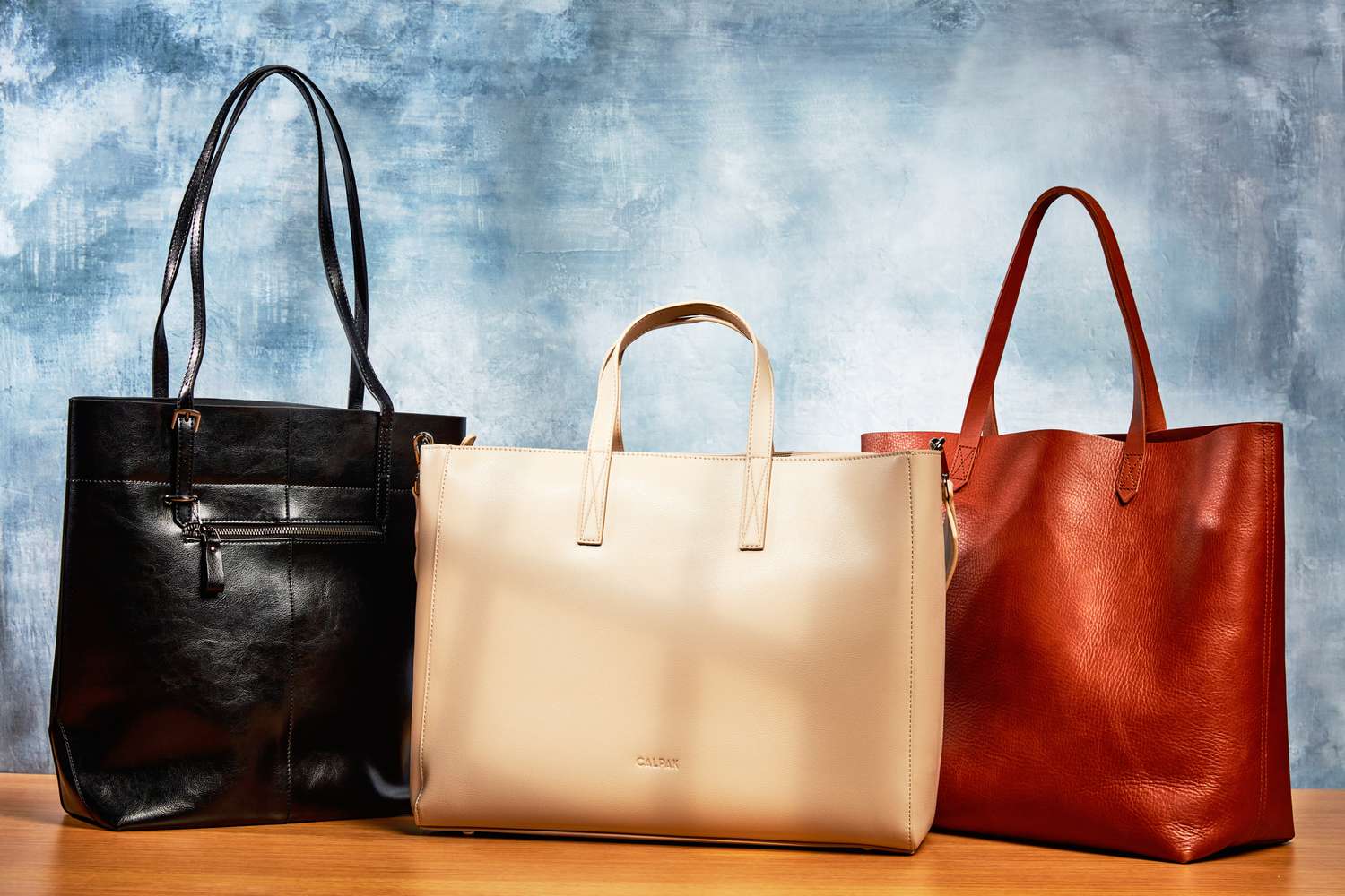 A selection of leather tote bags displayed against a blue background