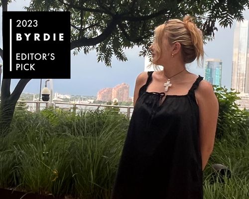 Byrdie editor Bella Cacciatore wears a black dress and silver cross necklace