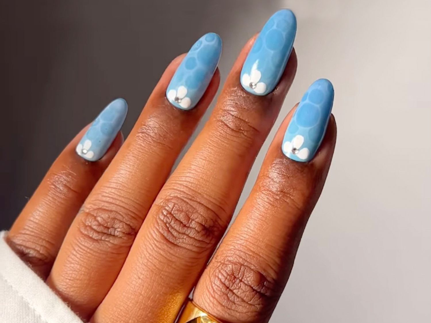 Light blue nails with a pool surface effect and white floral details at the cuticle.