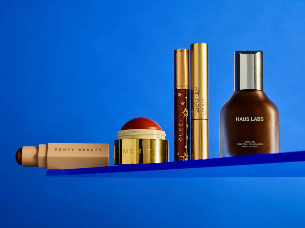 beauty products on a blue background on a plexiglass shelf fenty merit gucci haus labs