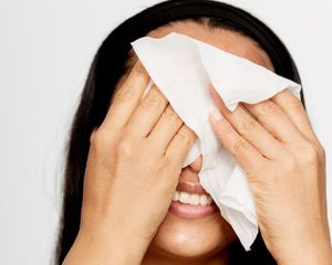 Woman wiping face with tissue