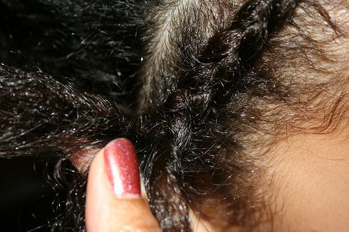 close up of fingers braiding a cornrow