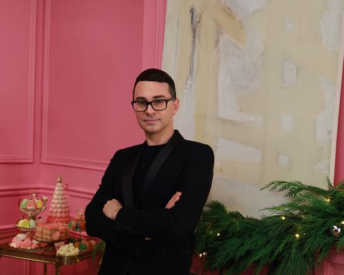 Christian Siriano stands in a pink room with holiday decor and treats