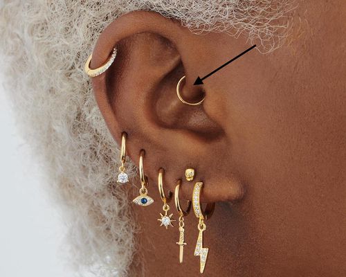 close up of woman's ear with gold daith piercing