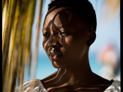 woman looking at sun through palm leaves