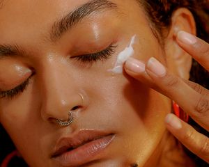 Woman applying cream to face