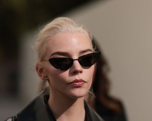 Anya Taylor-Joy wears black cat-eye sunglasses and a leather jacket