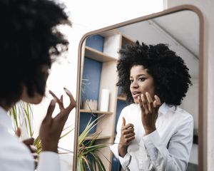 woman looking at sebaceous filaments in mirror