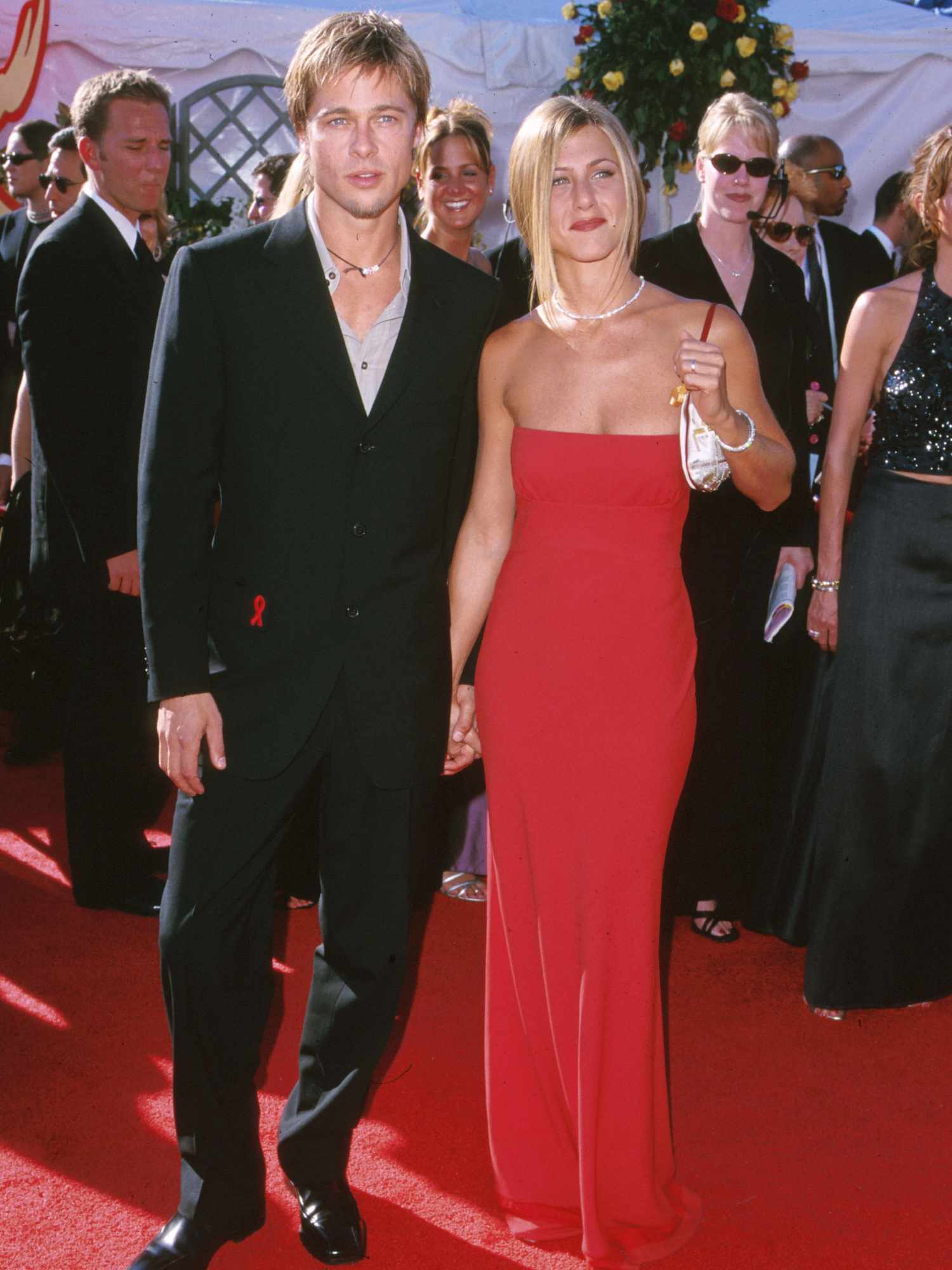 Jennifer Aniston wears a red floor-length gown, sparkly necklace, and silver handbag to the 2000 Emmy Awards