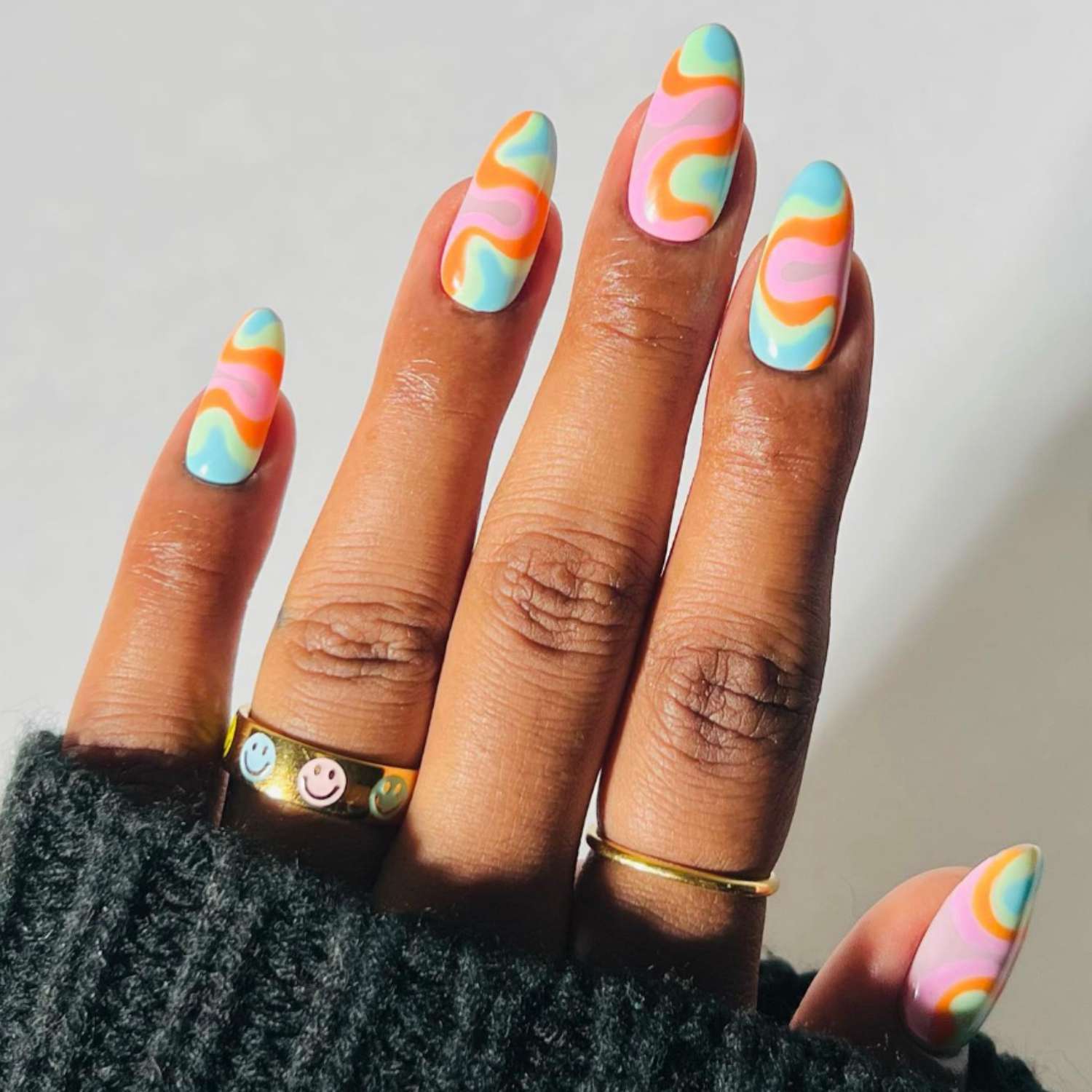 Manicure with pink, orange, blue, and green retro swirl design