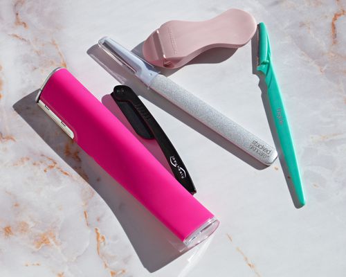 Assortment of the best dermaplaning tools we recommend on a marble surface