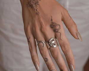 Close up of a hand with lots of small tattoos