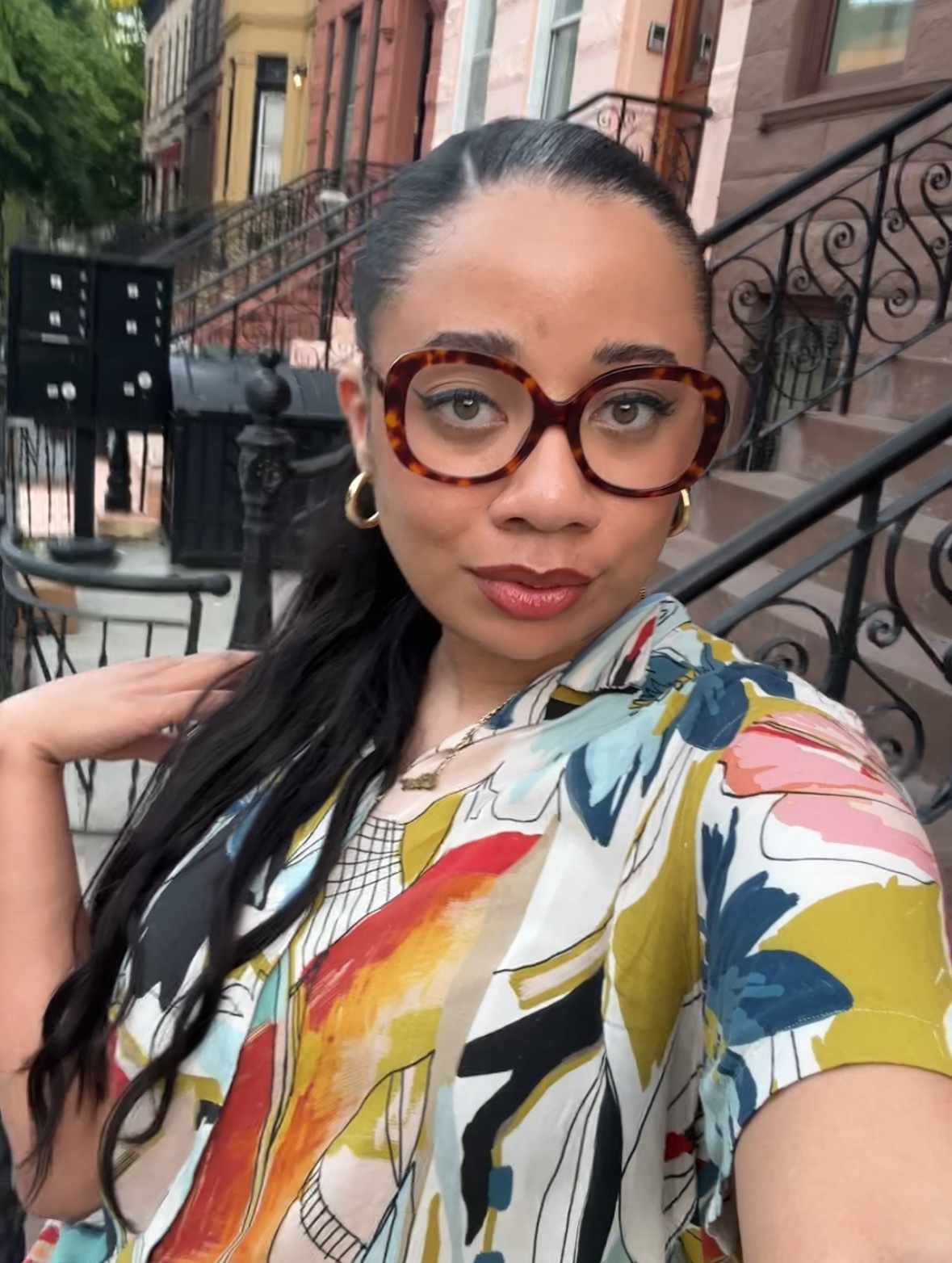 Photo of Byrdie editor Eden Stuart posing for a selfie wearing glasses with hair pulled back