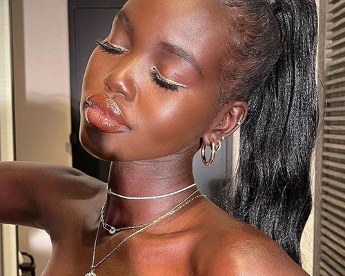 Adut Akech in a glossy makeup look with a high pony