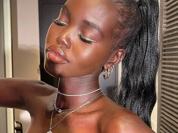 Adut Akech in a glossy makeup look with a high pony