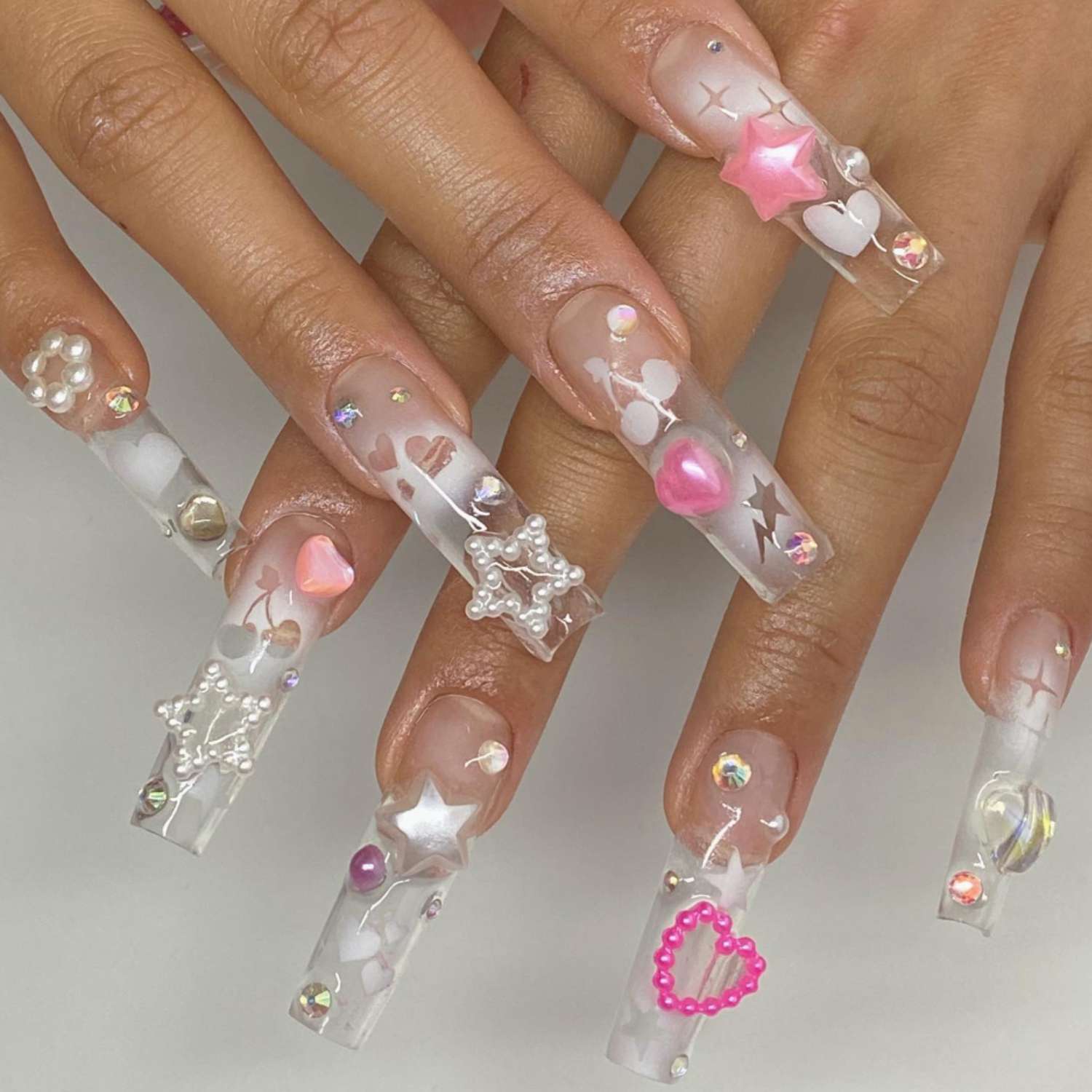 Clear nails with heart, star, cherry, pearl details, viewed up close