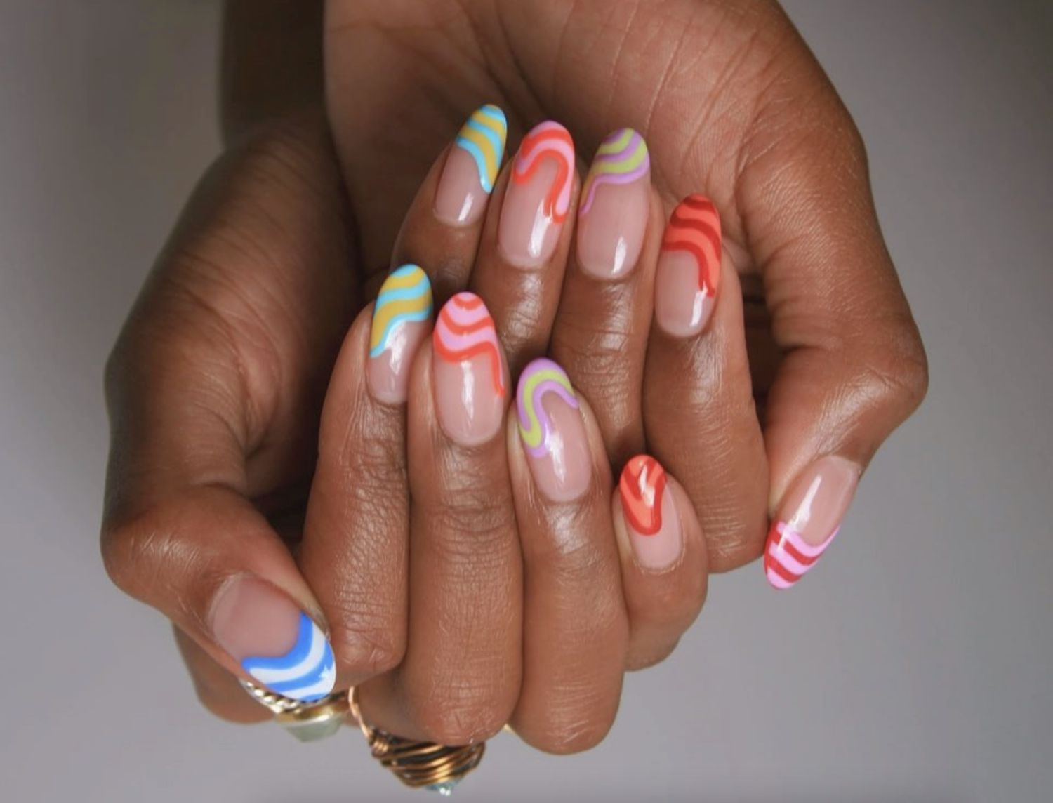 Almong-shaped nude nails with neon rainbow tips with a melting effect