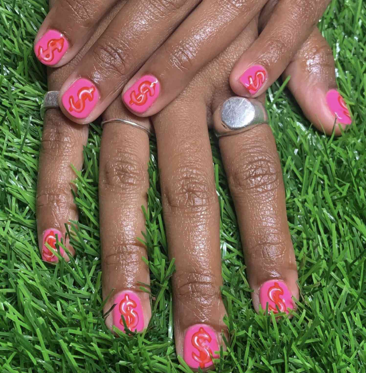 Short nails with neon pink dollar sign manicure