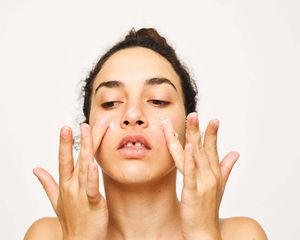 woman with tooth gap applying cream to cheeks with her fingers