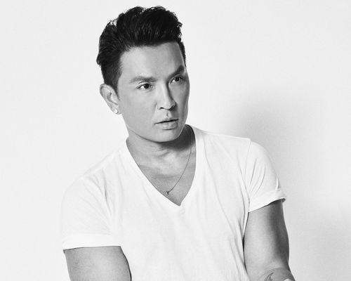 Black-and-white photo of Prabal Gurung wearing a white v-neck t-shirt and minimal necklace