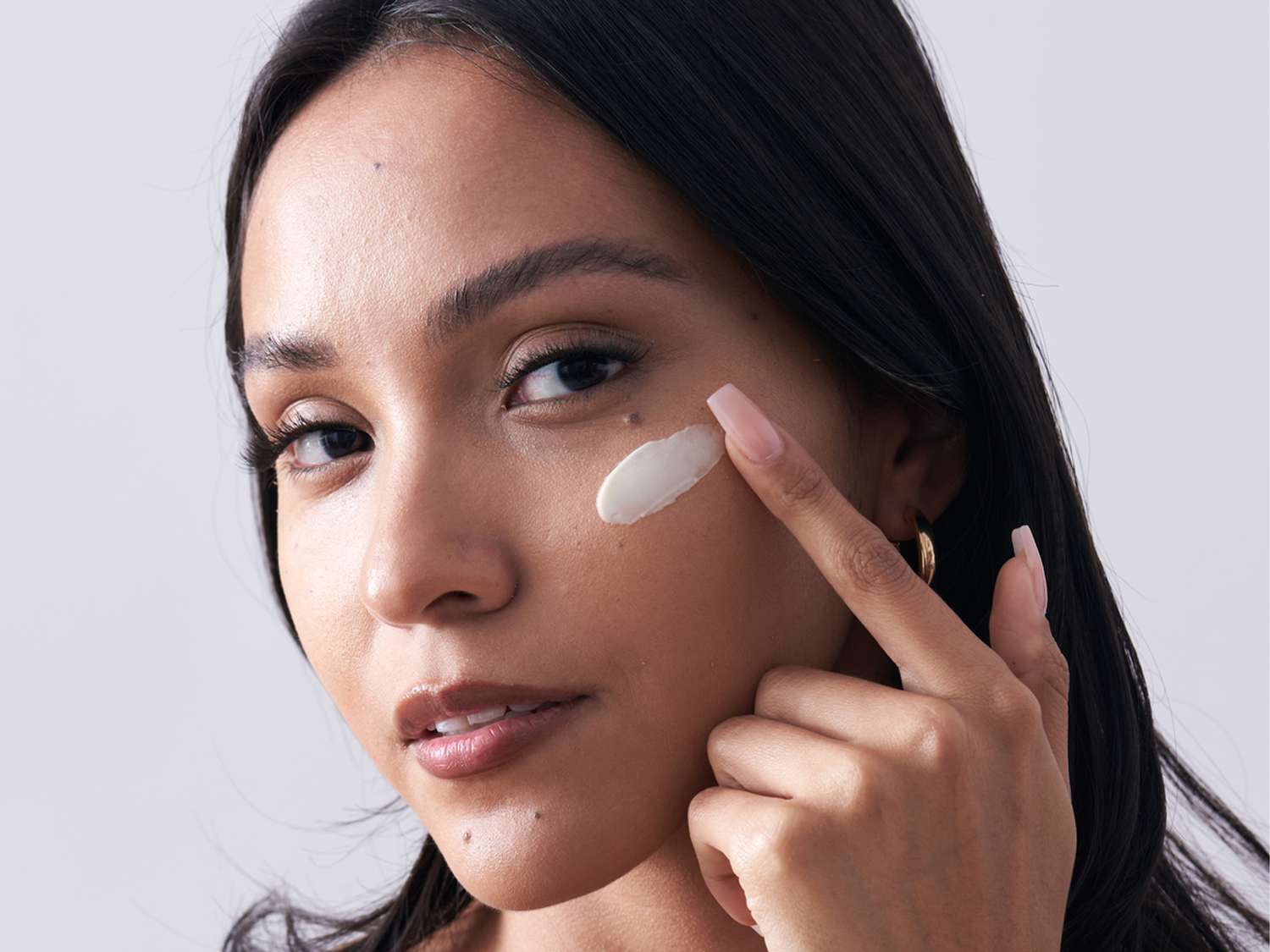 Latina Woman with Creamy Moisturizer Swatch on her Cheekbone