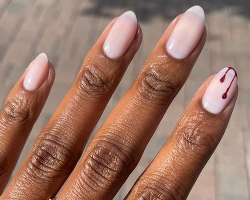 Close up of a milky manicure with one blood drip accent nail