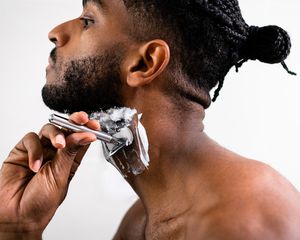 Man with shaving cream on his neck razoring off hair 