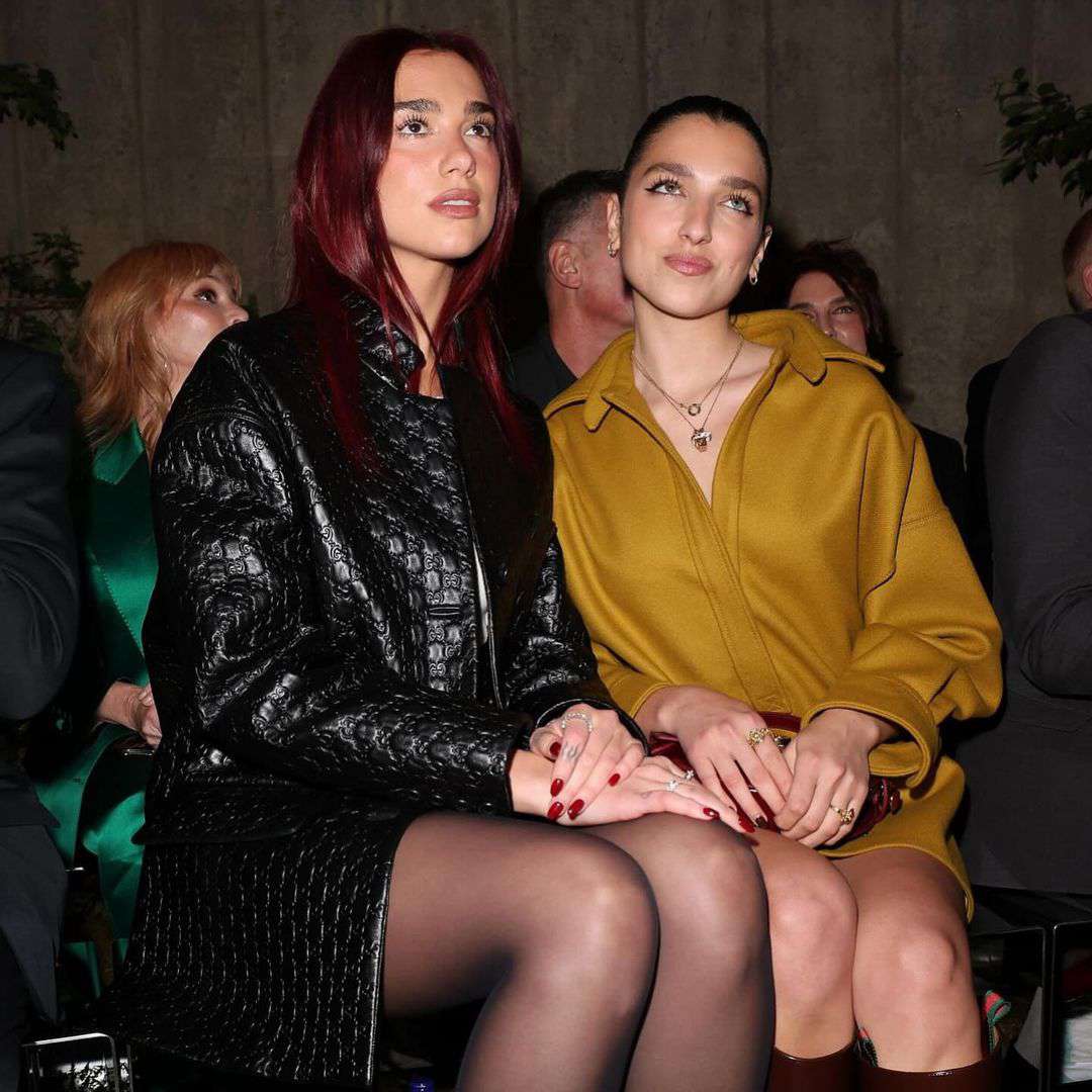 Dua Lipa in a black jacket posing with a guest at the Gucci runway show. 