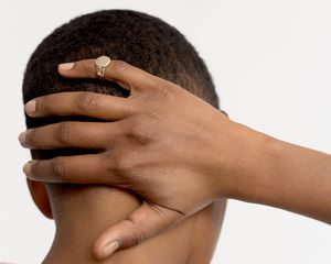 Rear view of a woman with a short haircut holding her on the back of her head