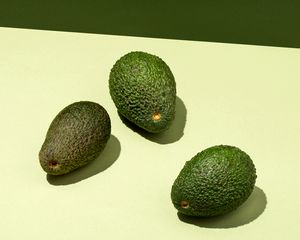 three avocados on a light green background